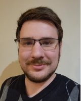 Friendly young man with stylish glasses and a warm smile in a cozy setting.